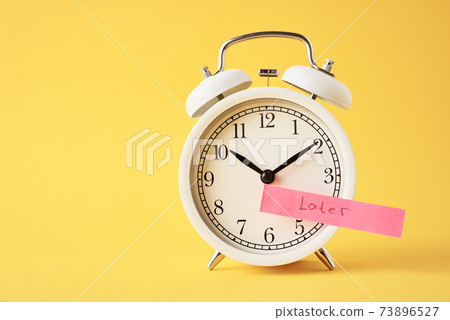 Procrastination and delay concept. Sticky note with word later on white alarm clock on yellow background. Urgency time Procrastination and delay concept. Sticky note with word later on white alarm clock on yellow background. Urgency time 73896527