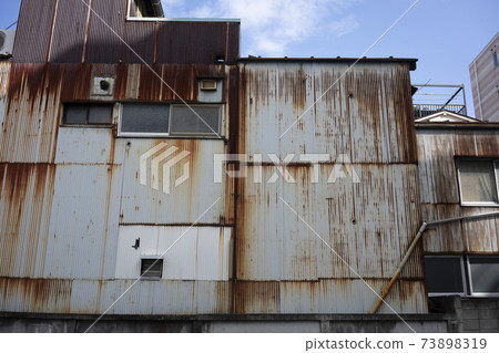 Rusted factory wall made of galvanized iron / construction site / town factory / ruins 73898319