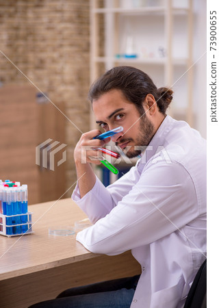 Young male chemist sitting at the desk in the classroom Young male chemist sitting at the desk in the classroom 73900655