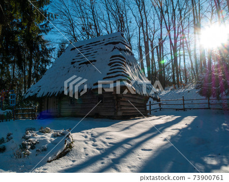 Wooden vintage country house in mountains forest covered snow on nature landscape. Active rest. Snowy winter holidays. 73900761
