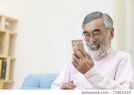 Senior male video call using a smartphone Senior male video call using a smartphone 73901410