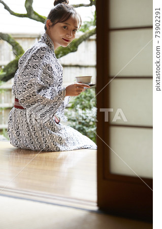 一個年輕的女人,穿著浴衣放鬆在一家旅館 一個年輕的女人,穿著浴衣放鬆在一家旅館 73902291