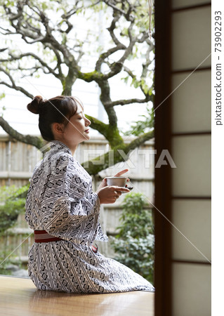 一個年輕的女人,穿著浴衣放鬆在一家旅館 一個年輕的女人,穿著浴衣放鬆在一家旅館 73902293