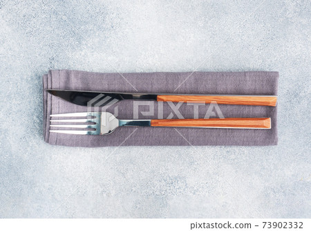 Cutlery knife and fork on a napkin, gray concrete background, copy space top view. 73902332