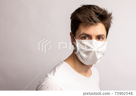 studio shot of a young man wearing a black mask, looking at camera, isolated on white background 73902548