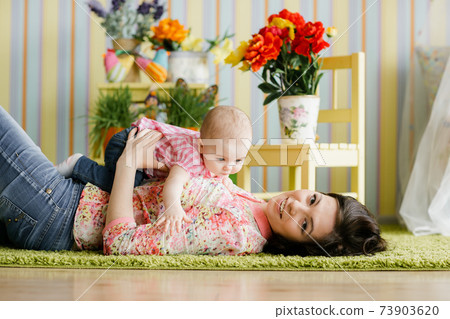Beautiful young woman and her charming little daughter are hugging and smiling 73903620