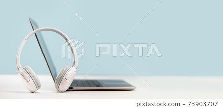 Laptop with headphones on white desk Laptop with headphones on white desk 73903707