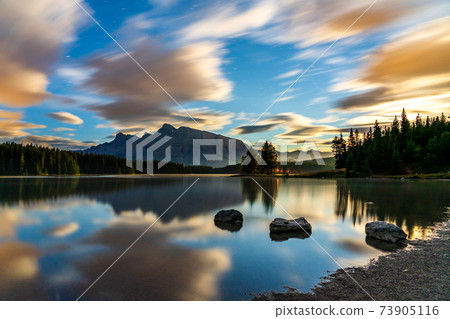 Two Jack Lake at daybreak, starry sky and colorful clouds reflected on the water surface. Beautiful landscape in Banff National Park, Canadian Rockies, Alberta, Canada. Two Jack Lake at daybreak, starry sky and colorful clouds reflected on the water surface. Beautiful landscape in Banff National Park, Canadian Rockies, Alberta, Canada. 73905116