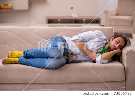 Young man drinking alcohol at home 73905782