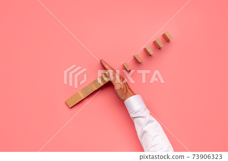 Top view of businessman stopping falling dominos Top view of businessman stopping falling dominos 73906323