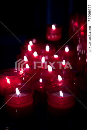 Many burning candles with red plastic sheath Many burning candles with red plastic sheath 73906635