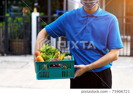 Asian delivery man delivering food, fruit, juice and vegetable to customer home - online grocery shopping service concept 73906721