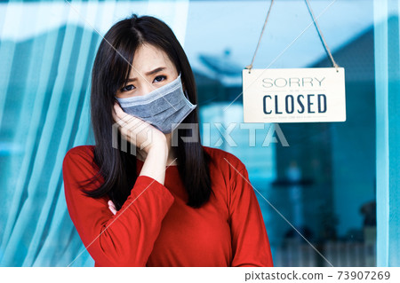 Asian woman shop owner hanging label 'Sorry we are Closed'. She close her shop under pandemic coronavirus 73907269