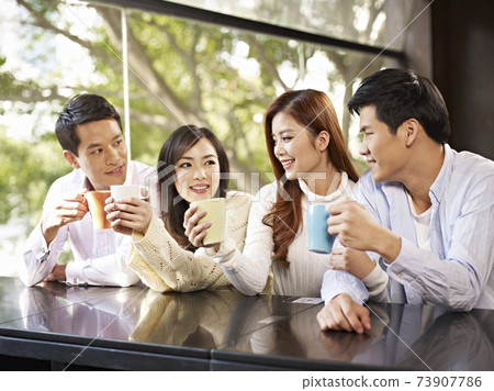 asian young adult friends having good time chatting in coffee shop 73907786