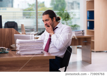 Young male employee and too many work in the office Young male employee and too many work in the office 73909768