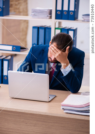 Young male employee and too many work in the office Young male employee and too many work in the office 73910440