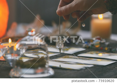 Hand with pendulum over tarot cards Hand with pendulum over tarot cards 73910620