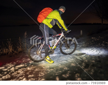 Mountain biker ride alone in snowy winter night. Icy road Mountain biker ride alone in snowy winter night. Icy road 73910989