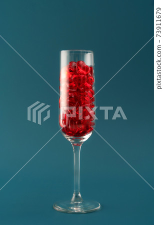 Beautiful card with champagne glass filled with transparent red hearts on dark aqua backdrop. Love and celebration concept. Great design for any purposes. 73911679