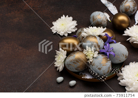 Easter Decoration with gray blue golden eggs, quail feathers, white flowers on dark wooden background. Selective focus, copy space. 73911754