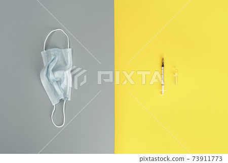 Syringe, ampoule and medical mask on trendy yellow and grey background. Medicine background. Coronavirus vaccine concept. 73911773