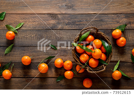 Tangerines, fresh mandarin oranges, clementines with leaves on wooden background. Top view, copy space Tangerines, fresh mandarin oranges, clementines with leaves on wooden background. Top view, copy space 73912615