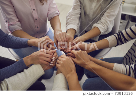 Group of women sitting together and holding hands, demonstrating support and solidarity Group of women sitting together and holding hands, demonstrating support and solidarity 73913156