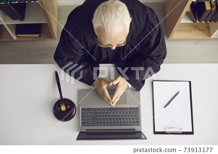 Trustworthy professional attorney or judge sitting at desk with laptop and gavel Trustworthy professional attorney or judge sitting at desk with laptop and gavel 73913177