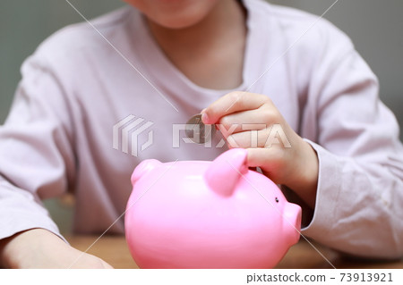 Girls put money in a piggy bank 73913921