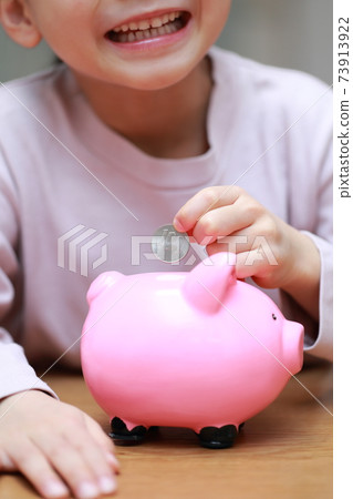 Girls put money in a piggy bank 73913922