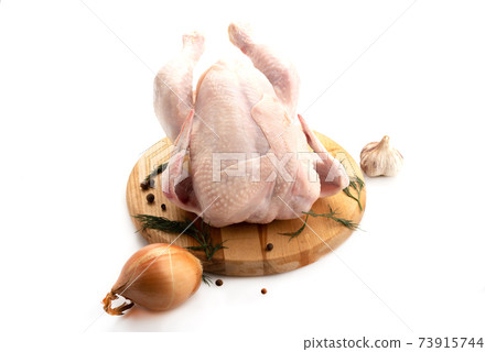 Fresh whole chicken on a cutting board with pepper, parsley, onion and garlic. Fresh whole chicken on a cutting board with pepper, parsley, onion and garlic. 73915744