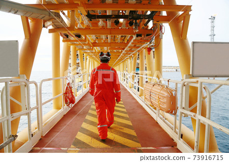 Offshore oil and gas industry and operated by technician petroleum. Worker walking to oil and gas plant for work as routine plan. Maintenance and Operation work scope in oil and gas plant. Offshore oil and gas industry and operated by technician petroleum. Worker walking to oil and gas plant for work as routine plan. Maintenance and Operation work scope in oil and gas plant. 73916715