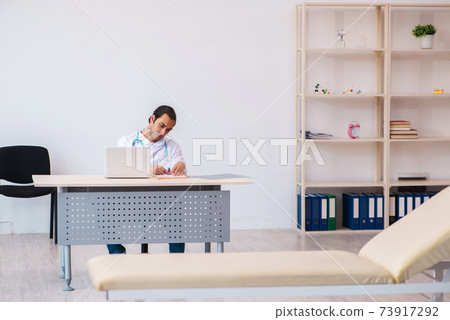 Young male doctor taking notes in the clinic 73917292