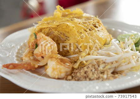 Pad Thai wrapped in egg on a white plate Pad Thai wrapped in egg on a white plate 73917543