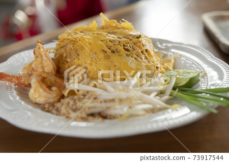 Pad Thai wrapped in egg on a white plate Pad Thai wrapped in egg on a white plate 73917544