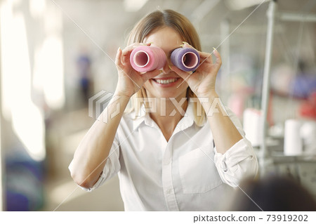 Woman standing in the factory with a thread Woman standing in the factory with a thread 73919202