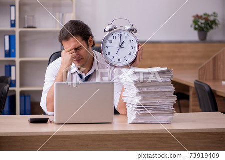 Young male employee in time management concept in the office 73919409