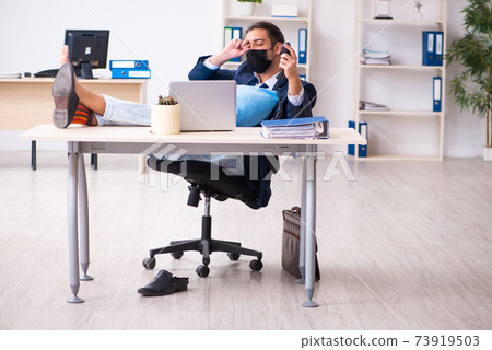 Young male employee during pandemic at workplace Young male employee during pandemic at workplace 73919503