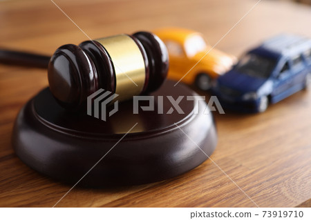 Judges wooden gavel lying on table near toy machines closeup 73919710