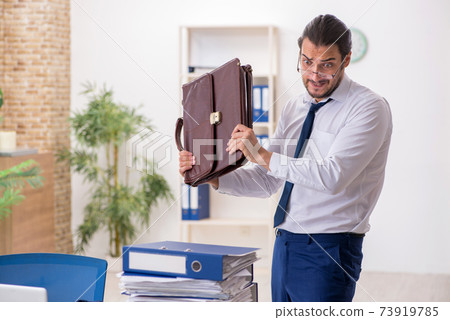 Young businessman unhappy with excessive work in the office Young businessman unhappy with excessive work in the office 73919785