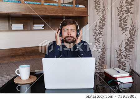 Satisfied businessman wearing headphones enjoying music at home Satisfied businessman wearing headphones enjoying music at home 73919805