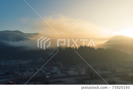 Mountains in the Morning. Majestic Sunrise in a Valley at Foggy Morning Mountains Landscape. Firs and Cozy Houses in Carpathians, Tatariv, Ukraine, Europe 73920193