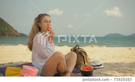 The cheerful woman in holding and eating slices of watermelon on tropical sand beach sea. Portrait attractive girl spend summer weekend. The cheerful woman in holding and eating slices of watermelon on tropical sand beach sea. Portrait attractive girl spend summer weekend. 73920383