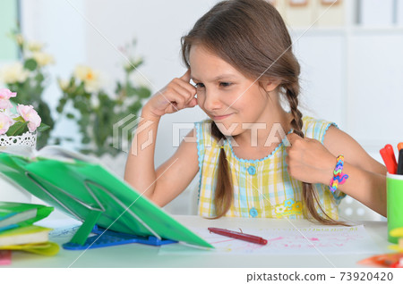 Portrait of cute little girl studying at home 73920420