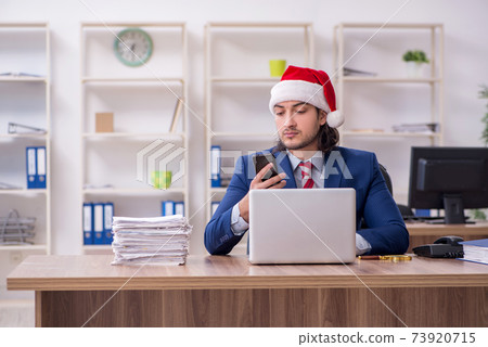 Young male employee working in the office at Christmas Eve Young male employee working in the office at Christmas Eve 73920715