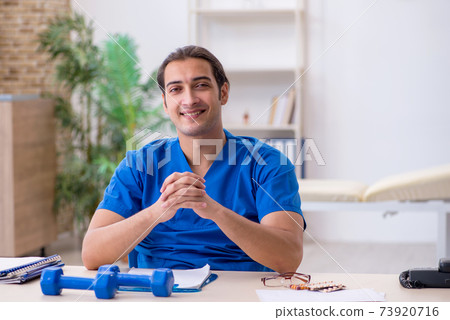 Young male doctor physiotherapist doing sport exercises 73920716