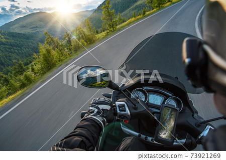 Motorcycle driver riding in Alpine route. 73921269