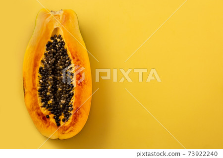 Half ripe papaya fruit on yellow background 73922240