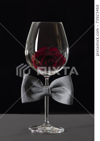 Wine glass with bow tie isolated on black background. International Bartenders Day. 73923468