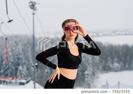 Female in sport wear snowboarder posing in sunglasses with snowboard Female in sport wear snowboarder posing in sunglasses with snowboard 73923543